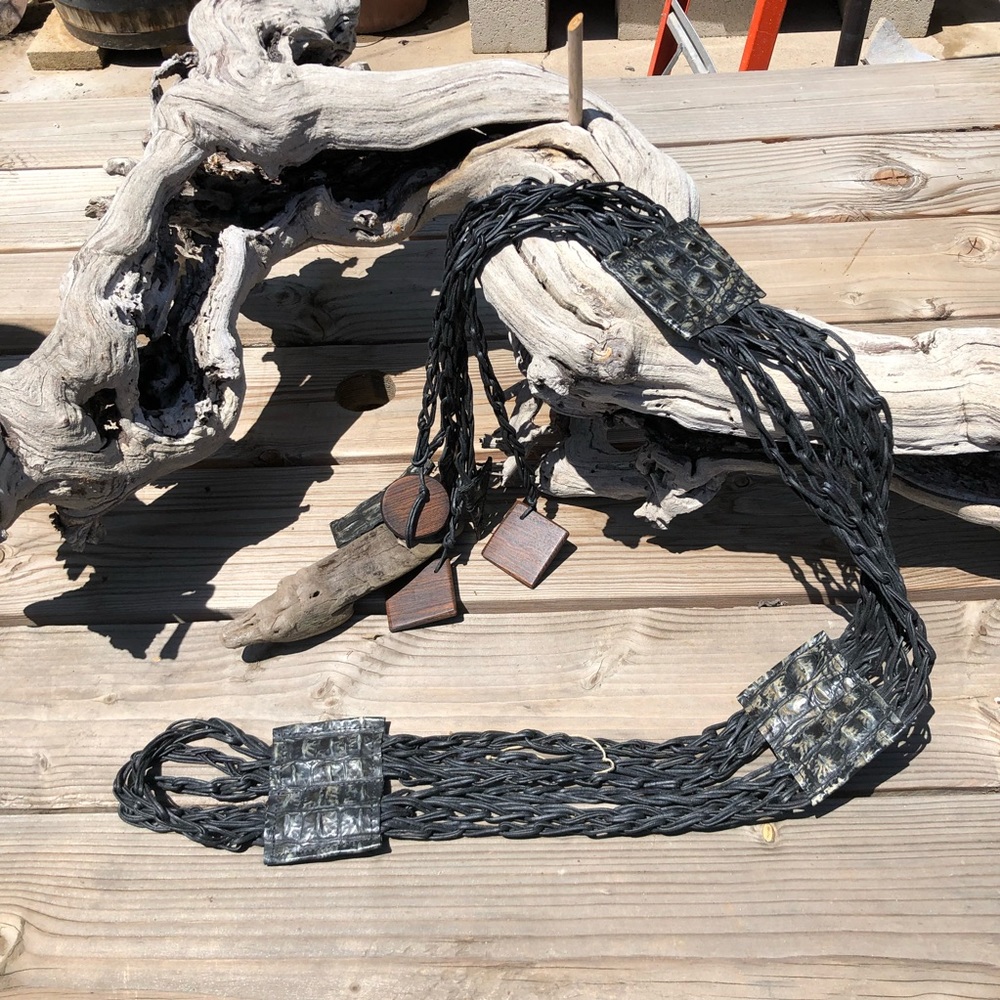 Black braided cord, embosed leather with geometric wooden accents.